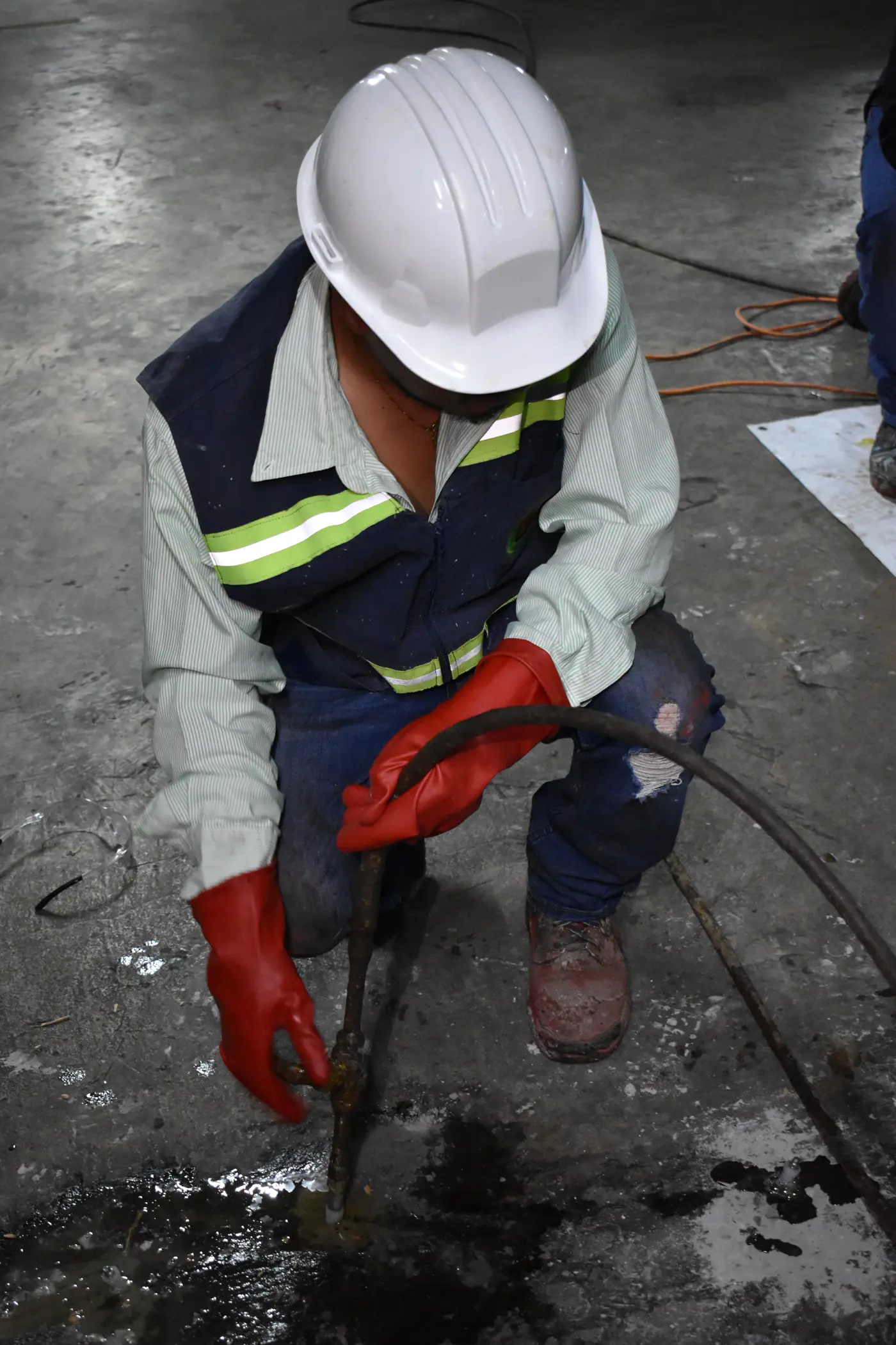 Técnico inyectando poliuretano a presión en losa de concreto